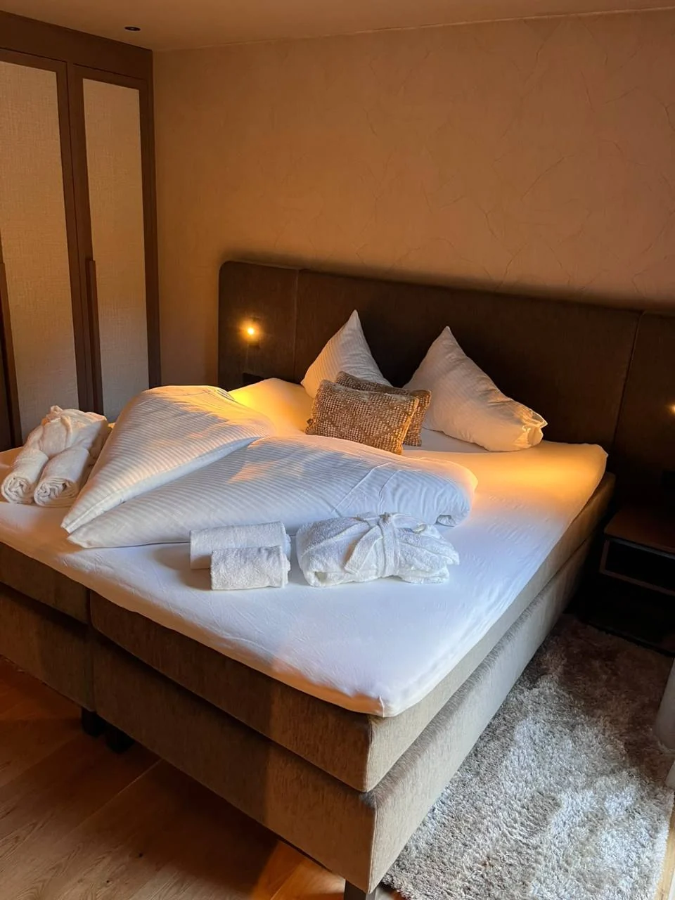 Hergerichtetes Doppelbett mit gefalteten Decken, Kissen und arrangierten Handtüchern
